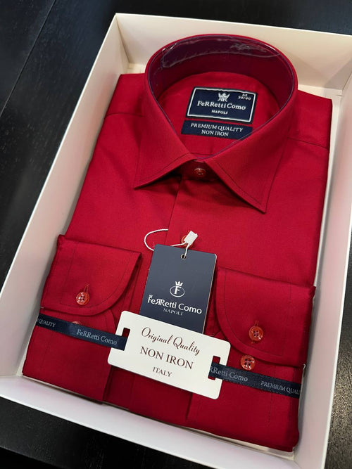 A folded red long-sleeve dress shirt with button-down front and chest pockets, presented inside a white gift box. The shirt has a dark blue neck label and a black hangtag reading 'FeRretti Como' and 'Original Quality NON IRON TENSILE'.